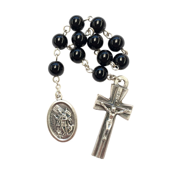 Black rosary beads with silver crucifix and medal on a white background